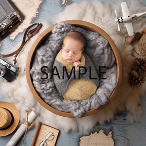 May include: A newborn baby wrapped in a gray and yellow swaddle, sleeping in a wooden bowl on a blue and brown world map background. There are various travel-themed props around the bowl, including a vintage camera, a suitcase, a hat, and a toy airplane.