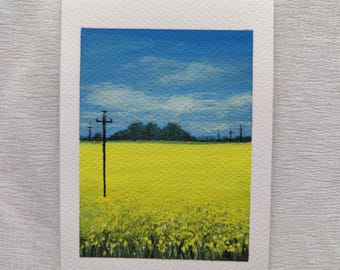 Könnte beinhalten: Ein kleines rechteckiges Gemälde auf strukturiertem weißem Papier, das ein leuchtend gelbes Blumenfeld unter einem hellblauen Himmel mit weißen Wolken zeigt. Ein hoher, dünner schwarzer Strommast steht markant im Vordergrund.