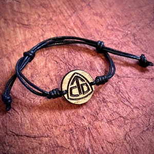 May include: A black cord bracelet with a wooden charm featuring the letters "GTO" in a triangular design.