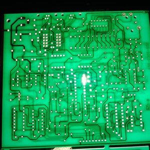May include: A green circuit board with a complex network of copper traces and solder points. The board has a white label with the text "200-8653-001" and "66C 0-1B".