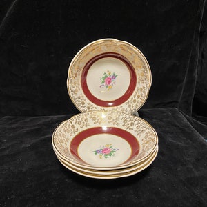 May include: Three white ceramic bowls with a burgundy rim and gold floral pattern. The bowls have a floral design in the centre.