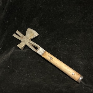 May include: A vintage multi-tool with a wooden handle and a metal head. The head features a hammer, a bottle opener, and a small axe. The handle is light brown, and the metal components are silver.