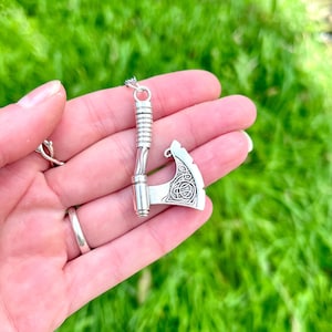 May include: Silver axe pendant with a Celtic knot design on the blade. The axe is on a silver chain.