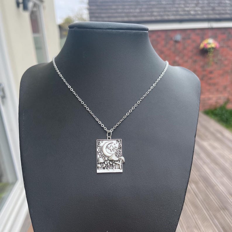 A black necklace display model wears the mushroom necklace. This is to demonstrate what the necklace will look like once being worn in real life.