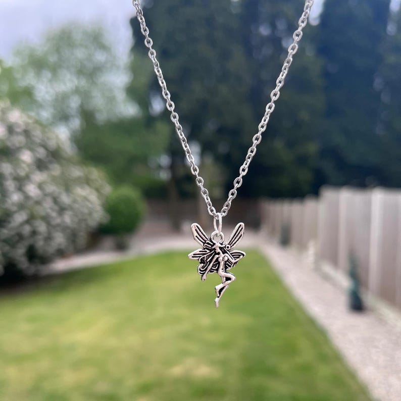 The fairy necklace dangles in front of a green grass background.