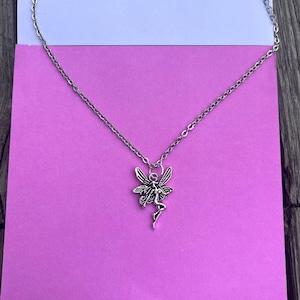 Another image of the fairy necklace placed against a pink background.