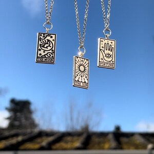 The three tarot card necklaces are dangling freely from the sky.