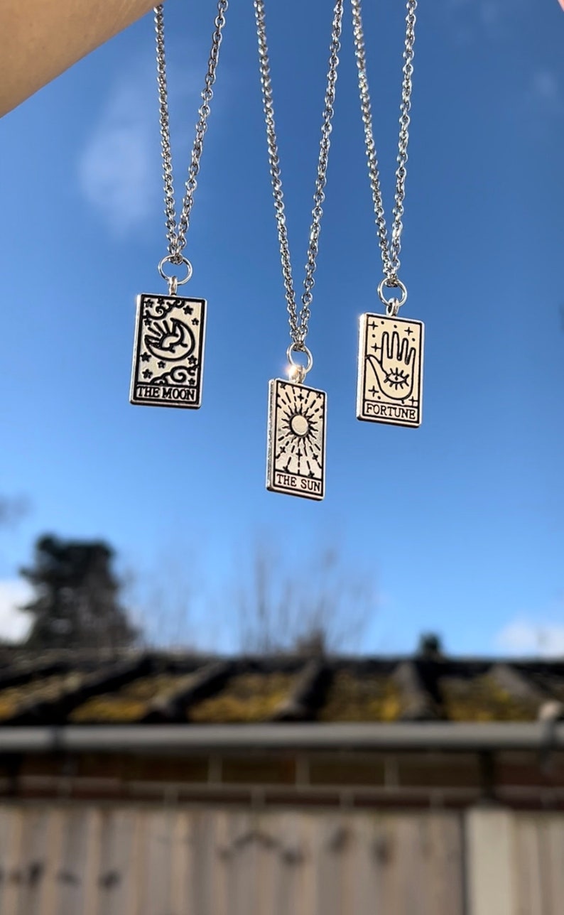 The three tarot card necklaces are dangling freely from the sky.