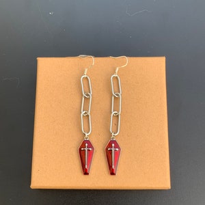 This image shows the earrings against a cardboard background.