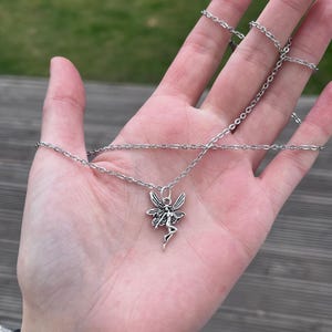 The model places the fairy necklace against the palm of her hands in this image. This is to be used as a size reference for the fairy pendant. For more specific measurements, please see the item description.