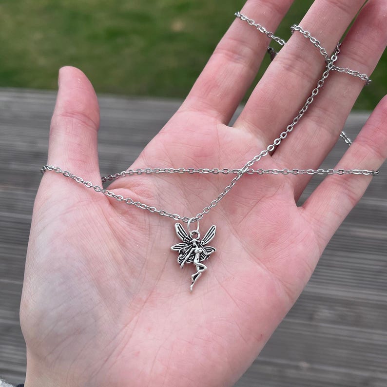 The model places the fairy necklace against the palm of her hands in this image. This is to be used as a size reference for the fairy pendant. For more specific measurements, please see the item description.