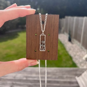 The mushroom necklace is placed against a plaque of wood.