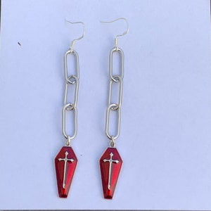 This image of the product is taken against a matte white background. The image was taken in natural daylight to best represent what the earrings look like in real life. The beautiful red shade of the coffin charms is really highlighted here.