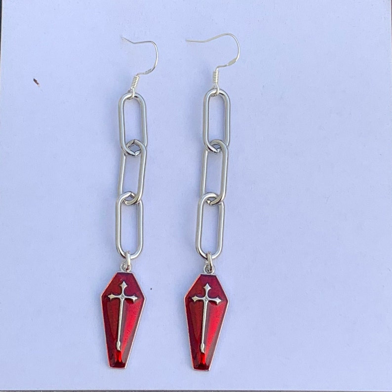 This image of the product is taken against a matte white background. The image was taken in natural daylight to best represent what the earrings look like in real life. The beautiful red shade of the coffin charms is really highlighted here.