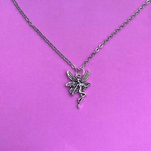 The fairy necklace is placed against a pink background in this photo. This is so that the lovely silver and black tones of the pendant can be seen in more detail.