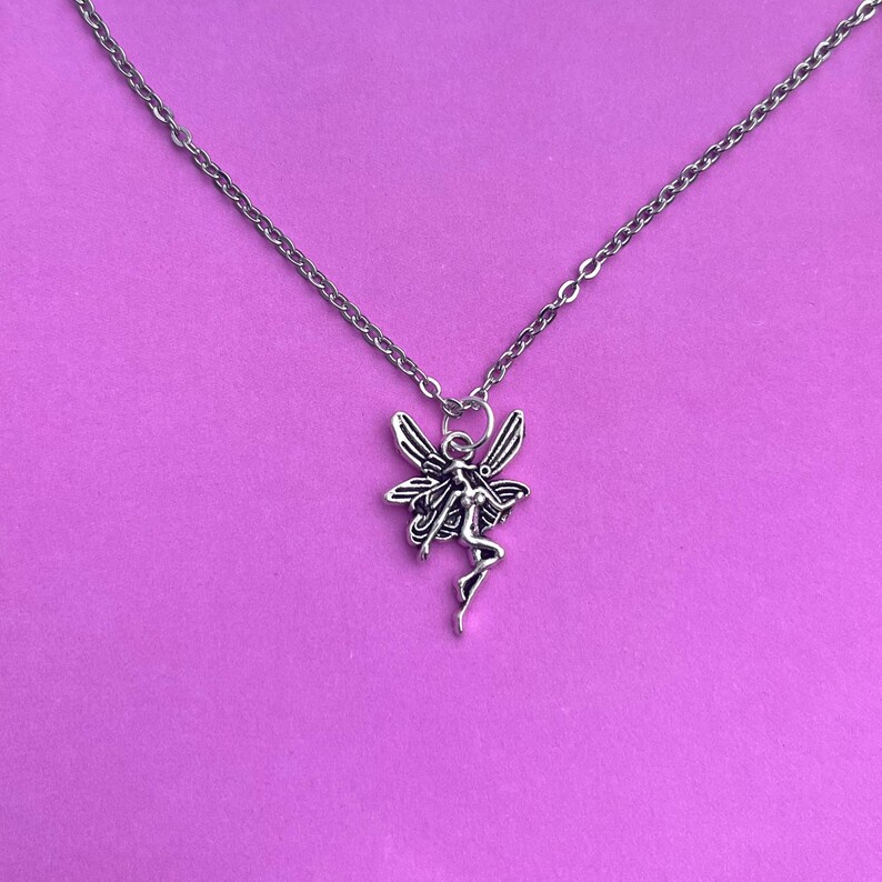 The fairy necklace is placed against a pink background in this photo. This is so that the lovely silver and black tones of the pendant can be seen in more detail.