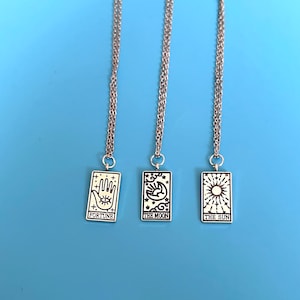 The necklaces are placed against a blue background. The detailing on the charms can be seen in more detail in this image.