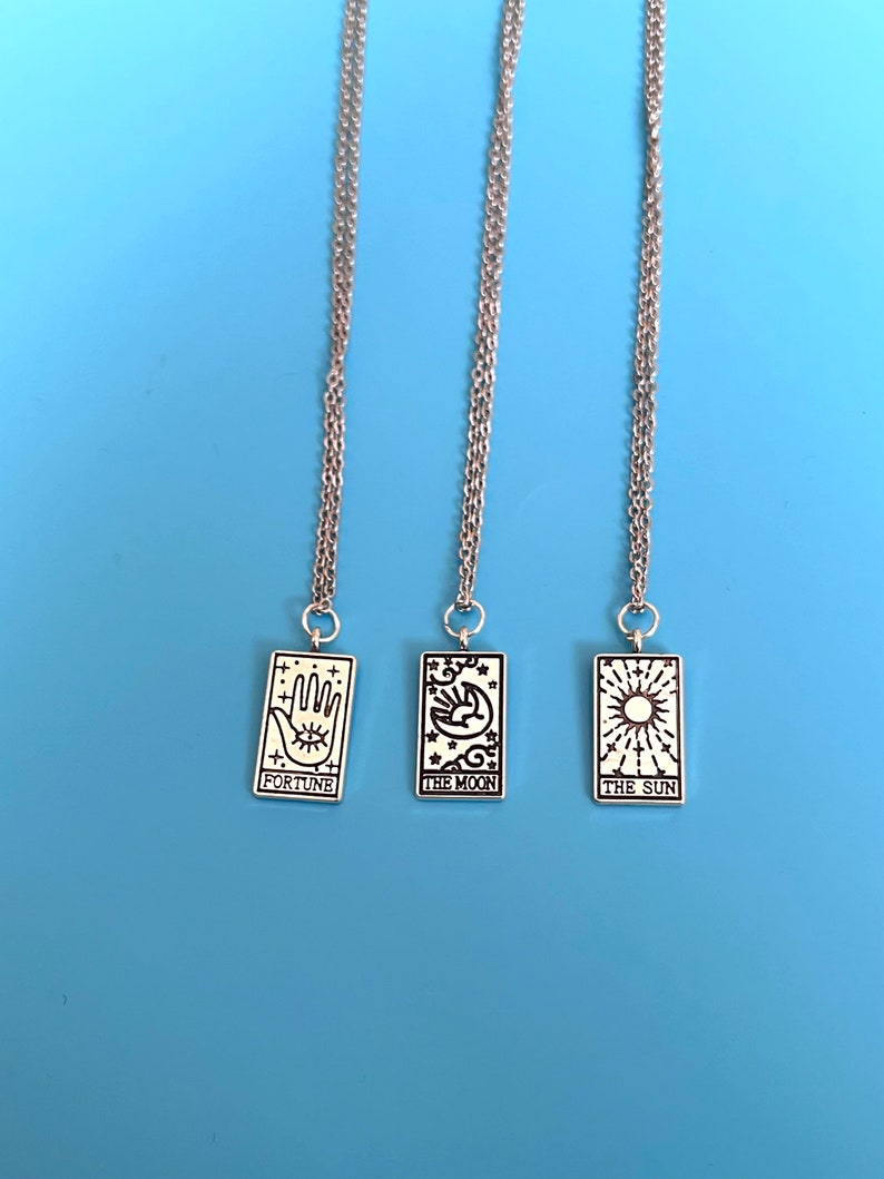 The necklaces are placed against a blue background. The detailing on the charms can be seen in more detail in this image.