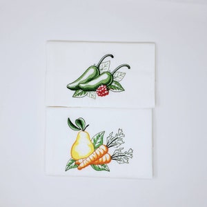 May include: Two embroidered kitchen towels. The top towel features two green chili peppers with a red raspberry and green leaves. The bottom towel features a yellow pear, two orange carrots, and green leaves.
