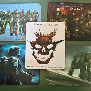 May include: Set of five square Halo-themed coasters. Each coaster features a different image of characters and logos from the Halo video game series. The coasters have a glossy finish and are in various shades of green, blue, and brown.