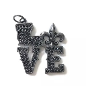 Pu&ograve; includere: Un ciondolo in metallo nero con la parola "LOVE" scritta in strass neri. La lettera "O" &egrave; sostituita da un design a giglio.
