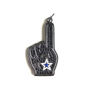 May include: A black metal charm in the shape of a hand with a raised index finger, covered in black rhinestones. The hand has a white star with a blue center.