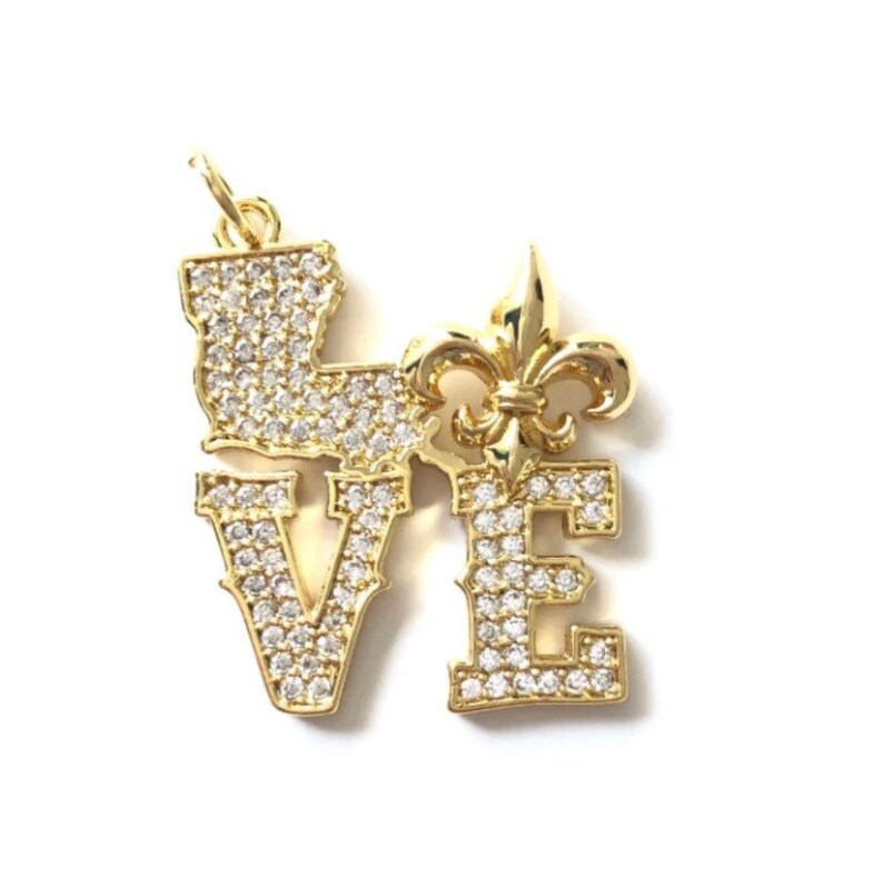 Pu&ograve; includere: Ciondolo pendente in oro con la parola "LOVE" scritta in lettere maiuscole con un giglio al centro. Ogni lettera &egrave; ricoperta di strass trasparenti.