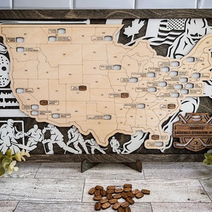 May include: A wooden map of the United States with hockey arenas marked. The map is framed in dark wood and features a hockey stick and puck design. The text "DUCKER HOCKEY STADIUM MAP" is visible on the map.