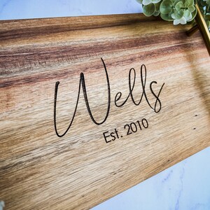 May include: A wooden serving tray with a gold handle. The tray is engraved with the text "Wells Est. 2010".