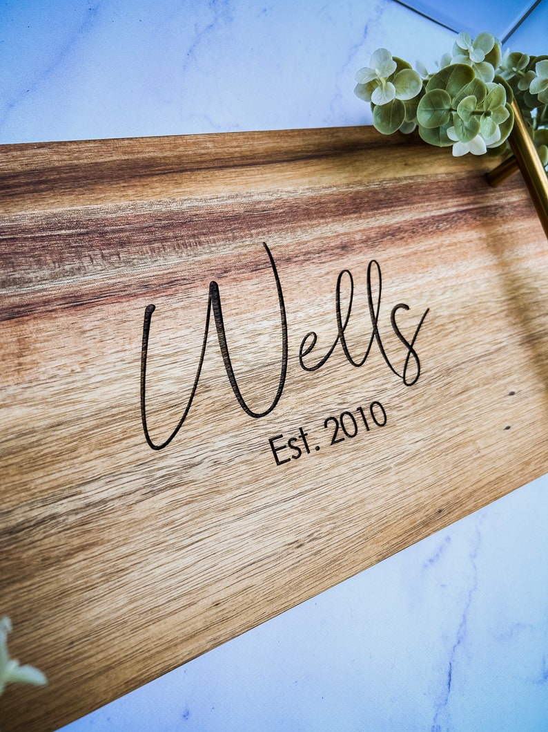 May include: A wooden serving tray with a gold handle. The tray is engraved with the text "Wells Est. 2010".