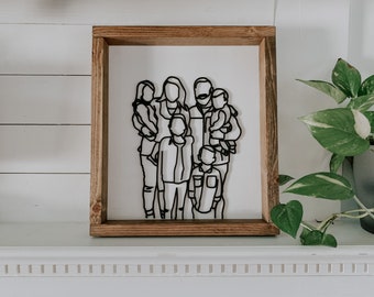 May include: A framed black and white line art illustration of a family of six. The illustration is in a rustic wooden frame.