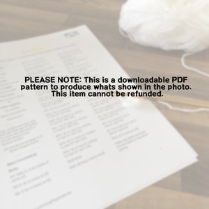 May include: A black and white printable PDF pattern for crocheting a white crocheted blanket. The text on the page reads "PLEASE NOTE: This is a downloadable PDF pattern to produce whats shown in the photo. This item cannot be refunded."