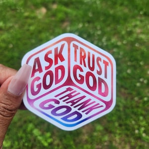May include: A colorful sticker with the words "ASK GOD", "TRUST GOD", and "THANK GOD" in a gradient of red, pink, and blue. The sticker is in a unique geometric shape.