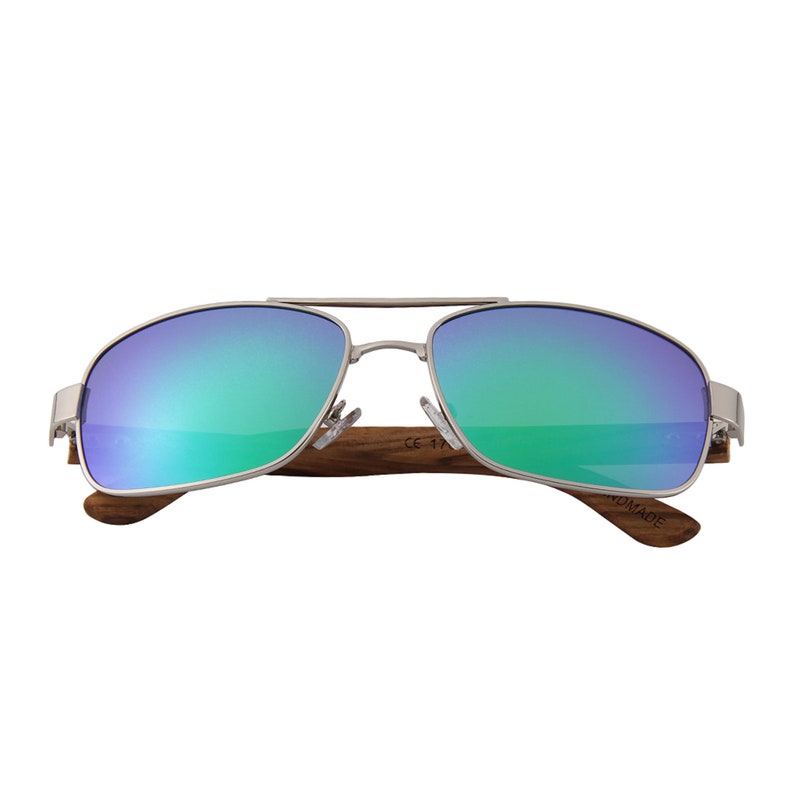 May include: Silver aviator sunglasses with green mirrored lenses and a wooden frame. The frame is marked "NOMADE" and "CE 17".