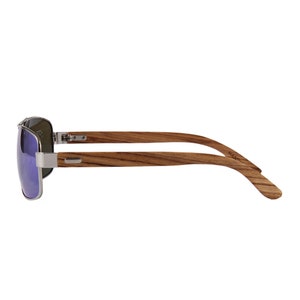 May include: A pair of aviator sunglasses with blue lenses and a wooden frame. The frame is made of brown wood with a natural grain pattern. The sunglasses have a silver metal hinge and a silver metal temple.