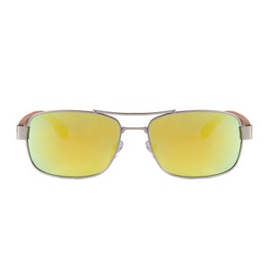 May include: Silver-framed sunglasses with mirrored yellow lenses. The sunglasses have a double bridge and wooden-look temples. The lenses reflect a bright yellow color, and the frame is a shiny silver.