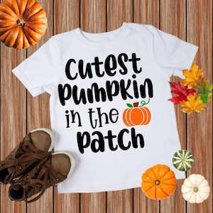 May include: White t-shirt with black text that reads "Cutest pumpkin in the patch" and a small orange pumpkin graphic.