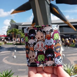 Pode incluir: Uma capa de tecido colorida com um padrão repetitivo de personagens de desenhos animados do filme Guardiões da Galáxia. Os personagens incluem Rocket Raccoon, Groot, Gamora e Star-Lord.