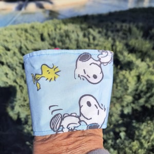Pode incluir: Uma caneca de cerâmica branca com uma alça preta e o texto "But First, Coffee" em negrito preto. A caneca está sobre um fundo neutro, destacando seu design simples.