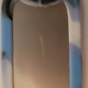 May include: A blue, black, and white camouflage dog tag with a silver ring.