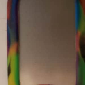 May include: A colorful, multi-colored, camouflage patterned dog tag with a silver metal insert and a round hole for a ring.