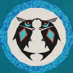 May include: A white circle with a blue and white patterned border. Inside the circle are two black fish facing each other with red and turquoise accents.