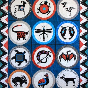 May include: A blue and white quilt with a geometric pattern of circles and triangles. Each circle contains a different animal or insect, including a ram, a frog, a bird, a cat, a dragonfly, an owl, a turtle, a lizard, a bat, a rabbit, a quail, and a deer. The quilt is made with a variety of fabrics and colors.