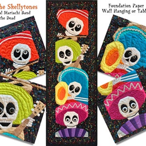 Op de afbeelding: Een kleurrijke, met papier gepatchte wandhanger of tafelkleed met een band van skeletmuzikanten die instrumenten bespelen. De skeletten dragen sombreros en traditionele Mexicaanse kleding. De achtergrond is zwart met muzieknoten en confetti.