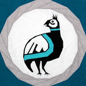 May include: A black and white stylized bird with a turquoise blue band around its neck. The bird is standing on a white background with a gray and white patterned border.