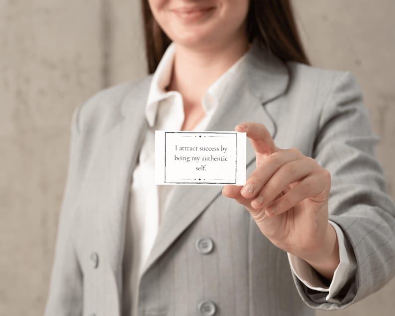 A woman dressed in a business suit holds a mantra card about attracting success.