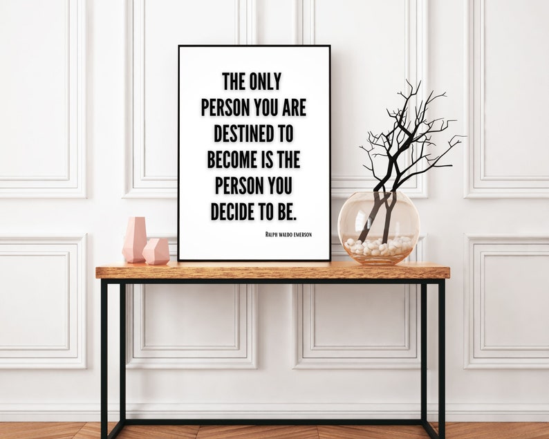 A motivational art print featuring a literary quote from Ralph Waldo Emerson sits on a decorative table in a home. The only person you are destined to become is the person you decide to be. Ralph Waldo Emerson.