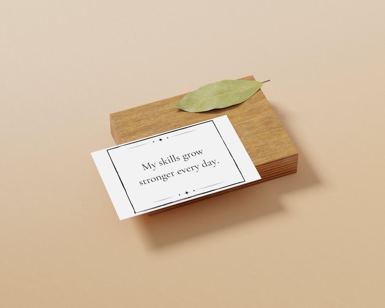 A mantra card about growing skills is shown on a wooden block with a leaf next to it. The block sits on a plain peach background.