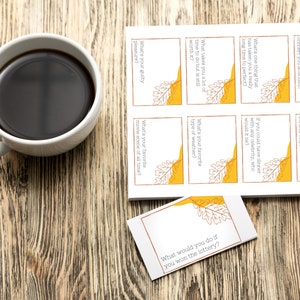 A sheet of Thanksgiving conversation starter cards sits next to a cup of coffee on a table.