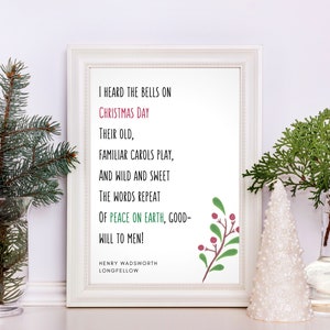Puede incluir: Una impresión enmarcada en blanco con un poema navideño de Henry Wadsworth Longfellow. El poema dice "Oí las campanas en el día de Navidad, Sus viejas canciones familiares tocan, Y salvajes y dulces las palabras se repiten, De paz en la tierra, buena voluntad para los hombres!"